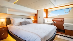 A modern, well-lit bedroom with a large bed, a bedside table, a nightstand, a built-in bench, and a window with a view of the sky. - Amazing 3 bedrooms luxury yacht in North Miami (North Miami)