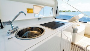 A boat's galley with a stainless steel sink, a warning sign, and a view of the water. - Amazing 3 bedrooms luxury yacht in North Miami (North Miami)