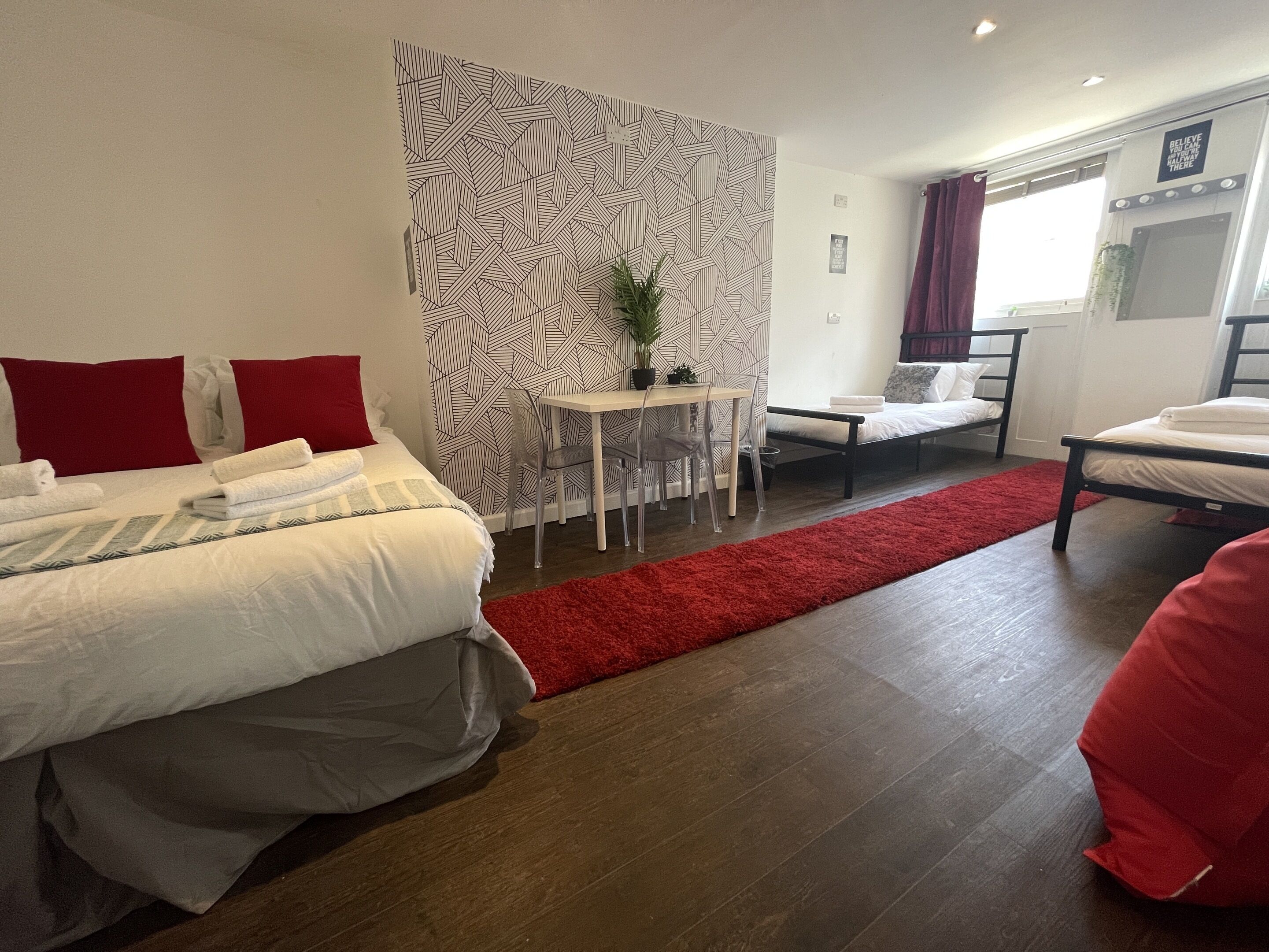 A modern hotel room with a large bed, a small desk, a chair, and a red rug.