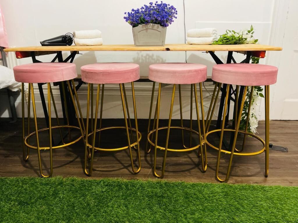 Un espacio de bar con cuatro taburetes rosas y una mesa de madera.