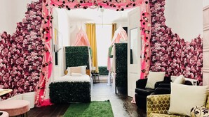 Ein Zimmer mit einem floral verzierten Bogen, der zu einem Bett, einem Sofa und einem kleinen Tisch führt.
