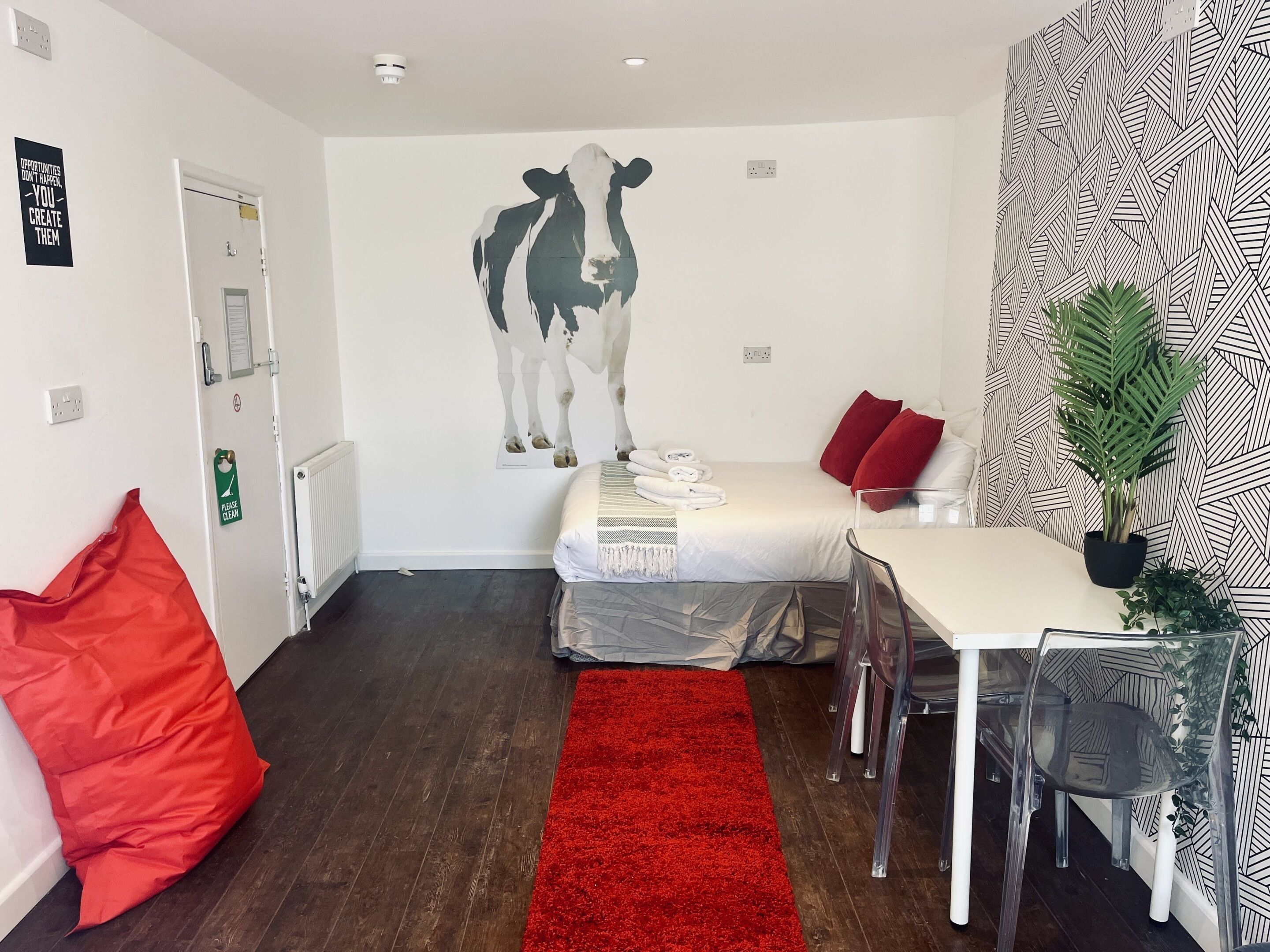 Una habitación de hotel pequeña con cama, escritorio y una alfombra roja.