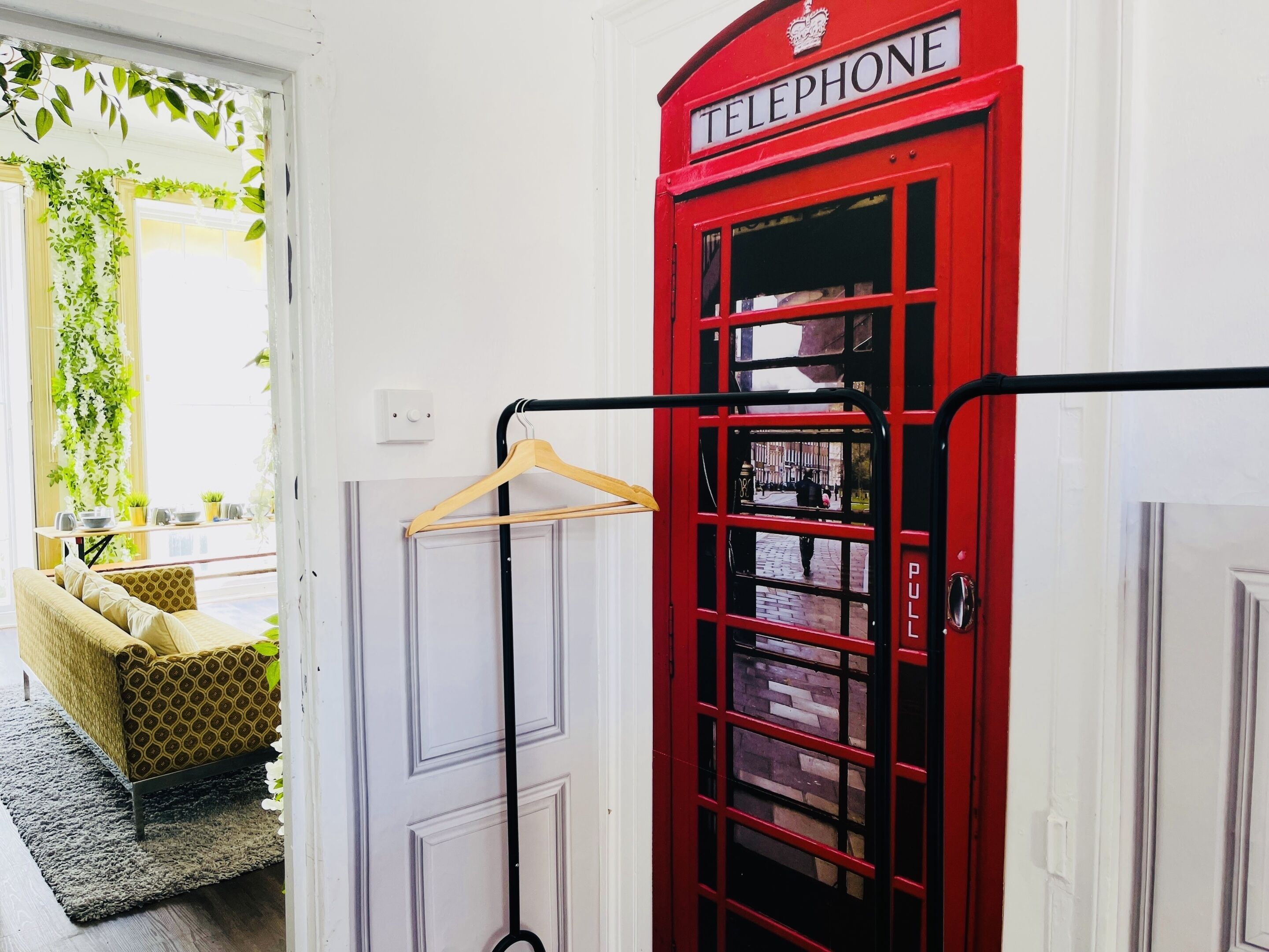 Uma cabine telefônica vermelha com um cabide de madeira e um puxador preto.