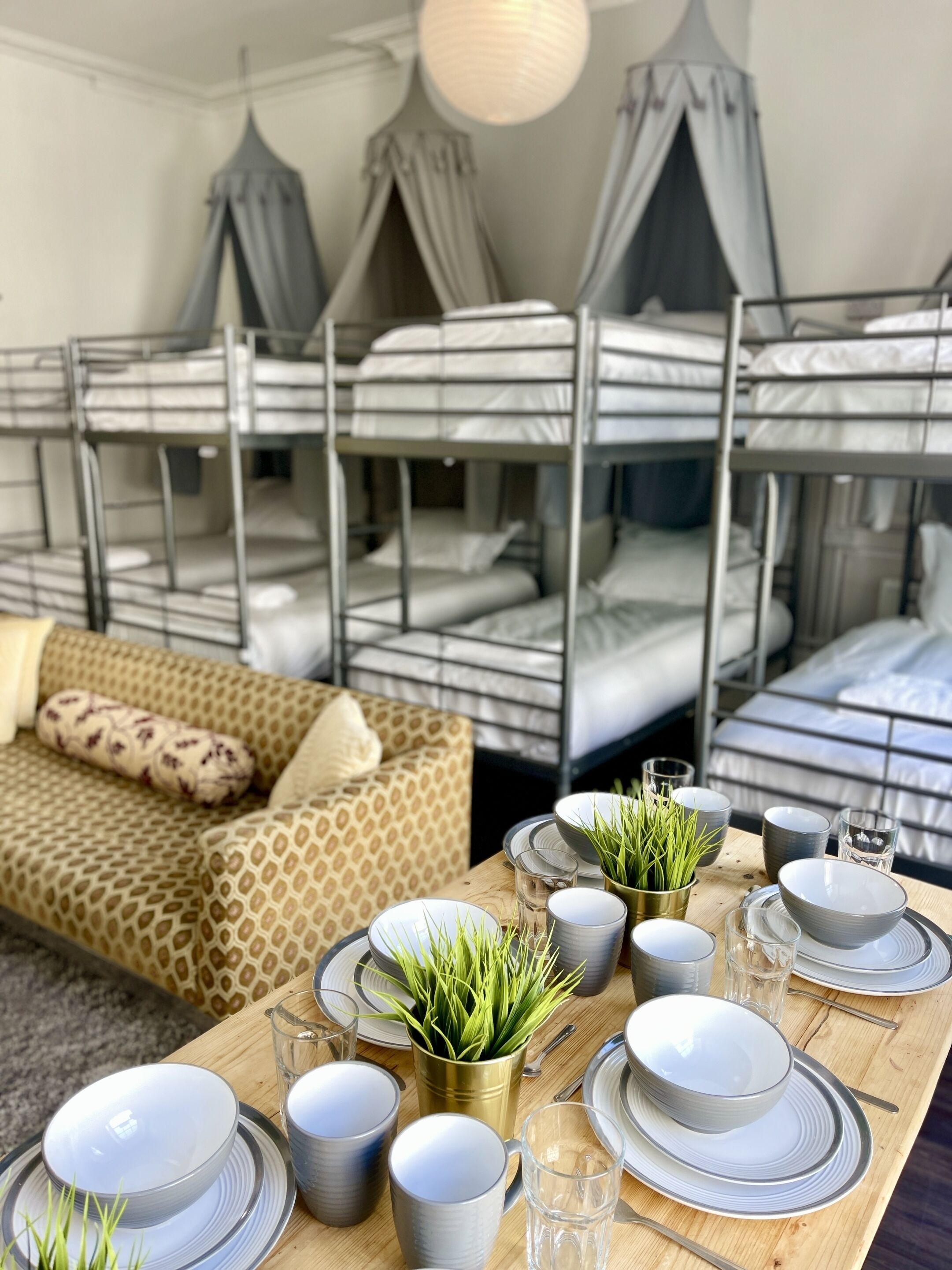 A room with bunk beds, a sofa, and a dining table set with plates, bowls, and glasses.