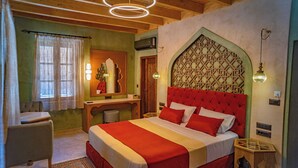 A bedroom with a large bed, a wooden desk, a mirror, and a decorative wall panel. - Fabrizio del Carretto (Rhodes)
