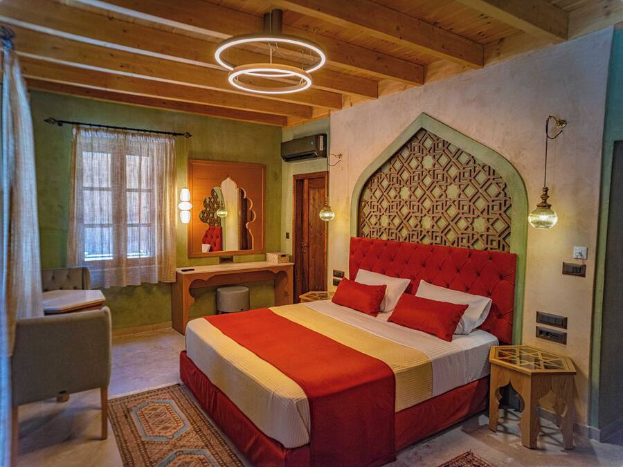 Un dormitorio con una cama grande, un escritorio de madera, un espejo y un panel decorativo en la pared.