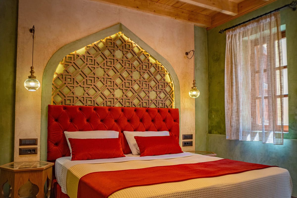 A bedroom with a large bed, a wooden ceiling, and a patterned headboard.
