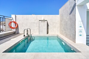 Una piscina con un flotador salvavidas, una escalera metálica y una placa adherida a la pared.
