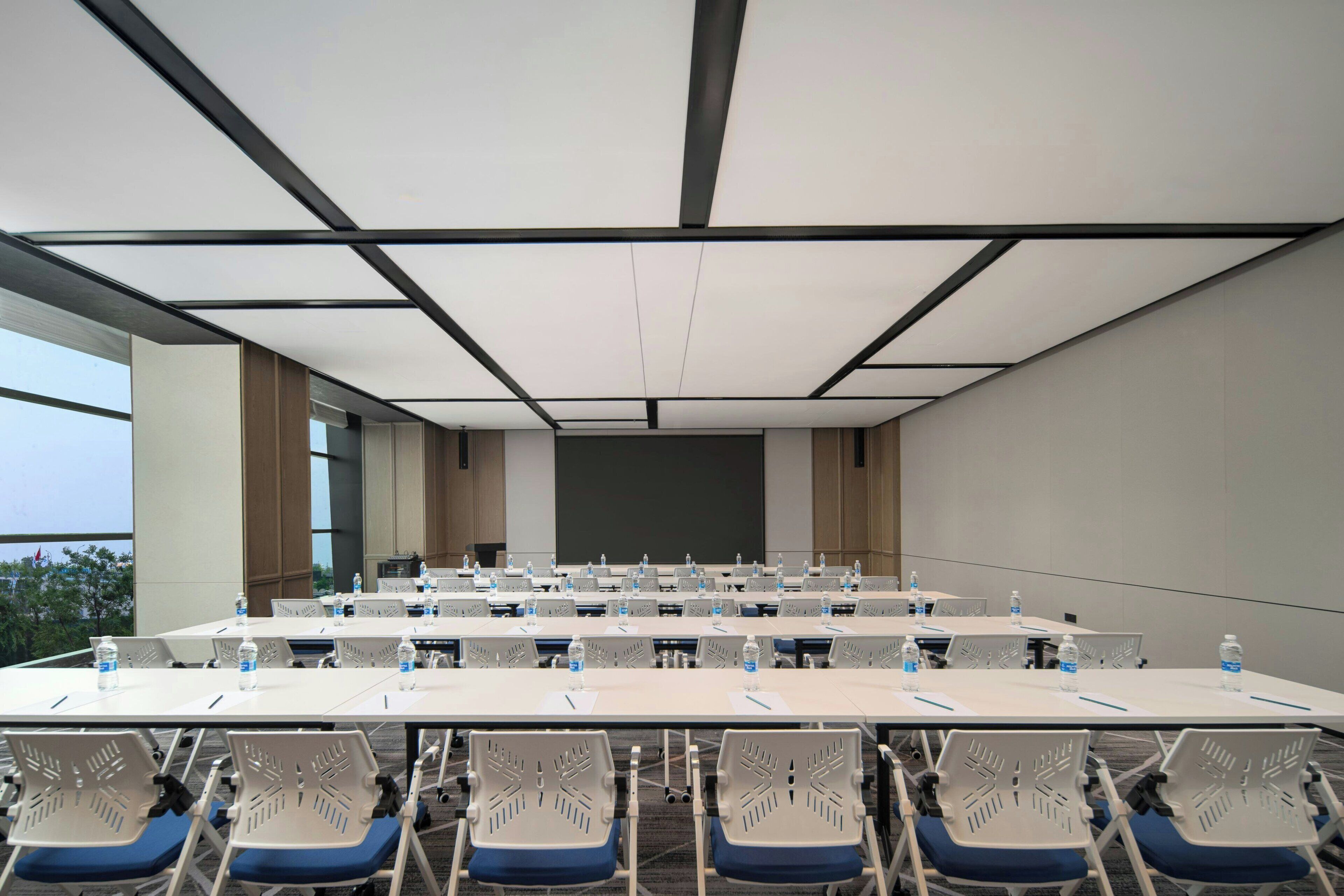 A conference room with multiple tables and chairs, equipped with water bottles and nameplates.