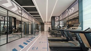 Un gimnasio moderno con cintas de correr, equipo de ejercicio y paredes espejadas.