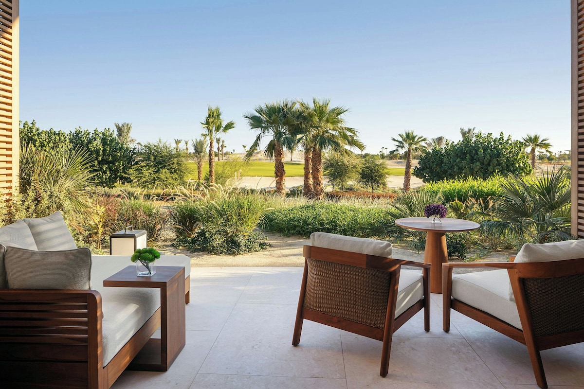 An outdoor seating area with wicker furniture and a view of a golf course.