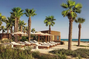 Playa privada, arena blanca, camas de playa, sillas reclinables de playa