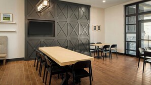 A conference room with a long table, chairs, a TV screen, and a large window. - Fairfield by Marriott Inn & Suites Perry (Perry)