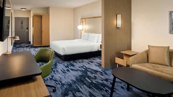 Una habitación de hotel con cama, escritorio, silla, sofá y televisión.