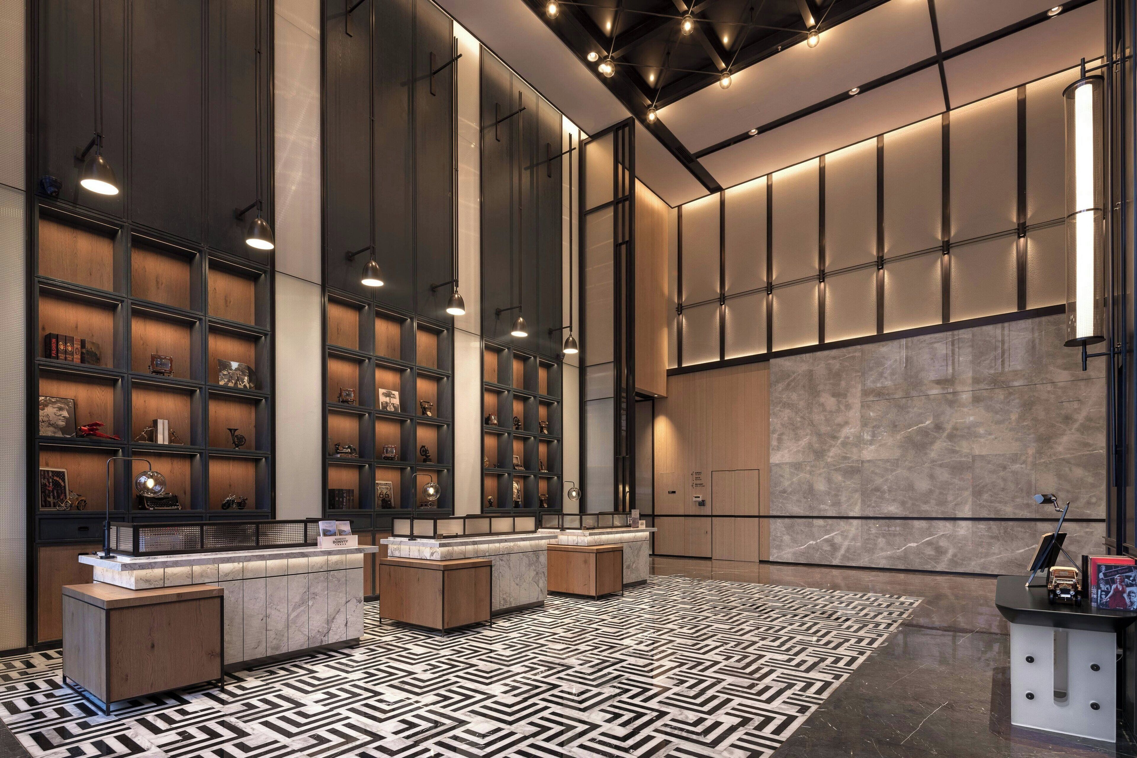 A modern lobby with a reception desk, shelving units, and a patterned floor.