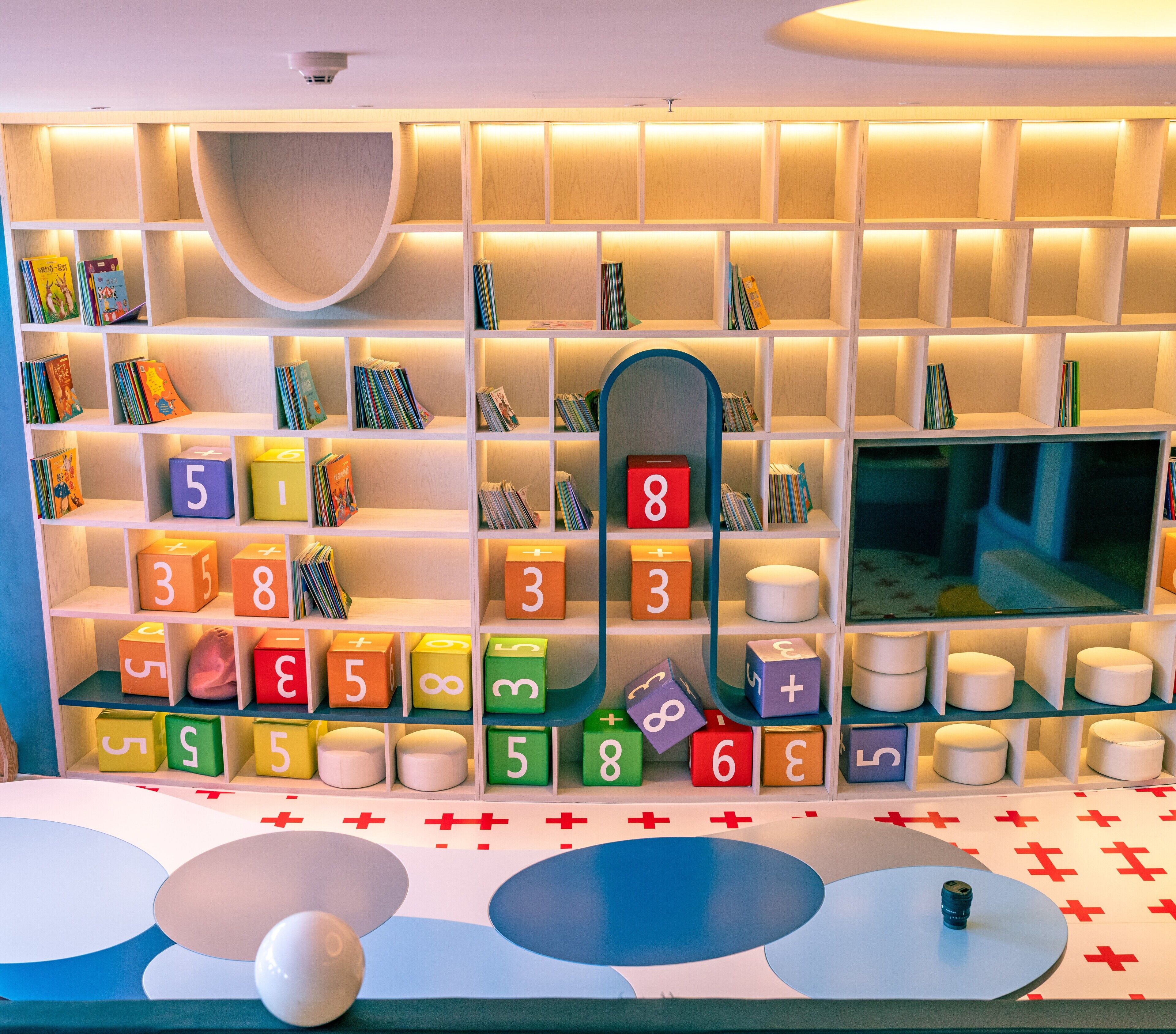 A children's play area with colorful blocks, a television, and a soft seating area.