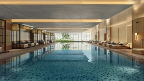 A modern indoor swimming pool with lounge areas on both sides, large windows, and a clear view of the outdoors. - Sheraton Kunshan Dianshan Lake (Suzhou)