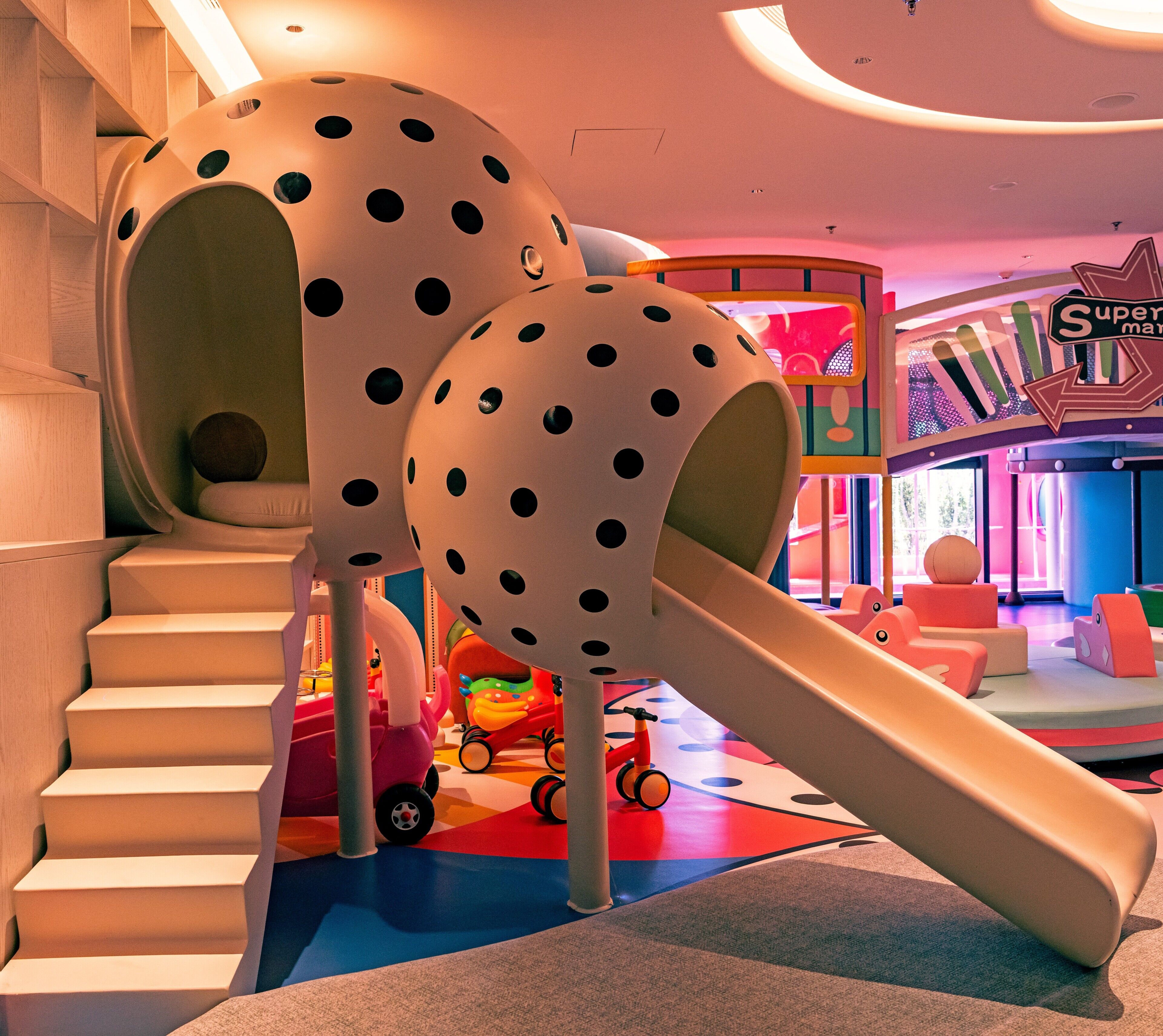 A children's play area with a slide, climbing steps, and colorful play structures.