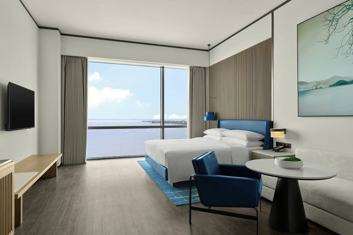 Een moderne hotelkamer met een groot bed, een bureau, een stoel, een tafeltje en een televisie.