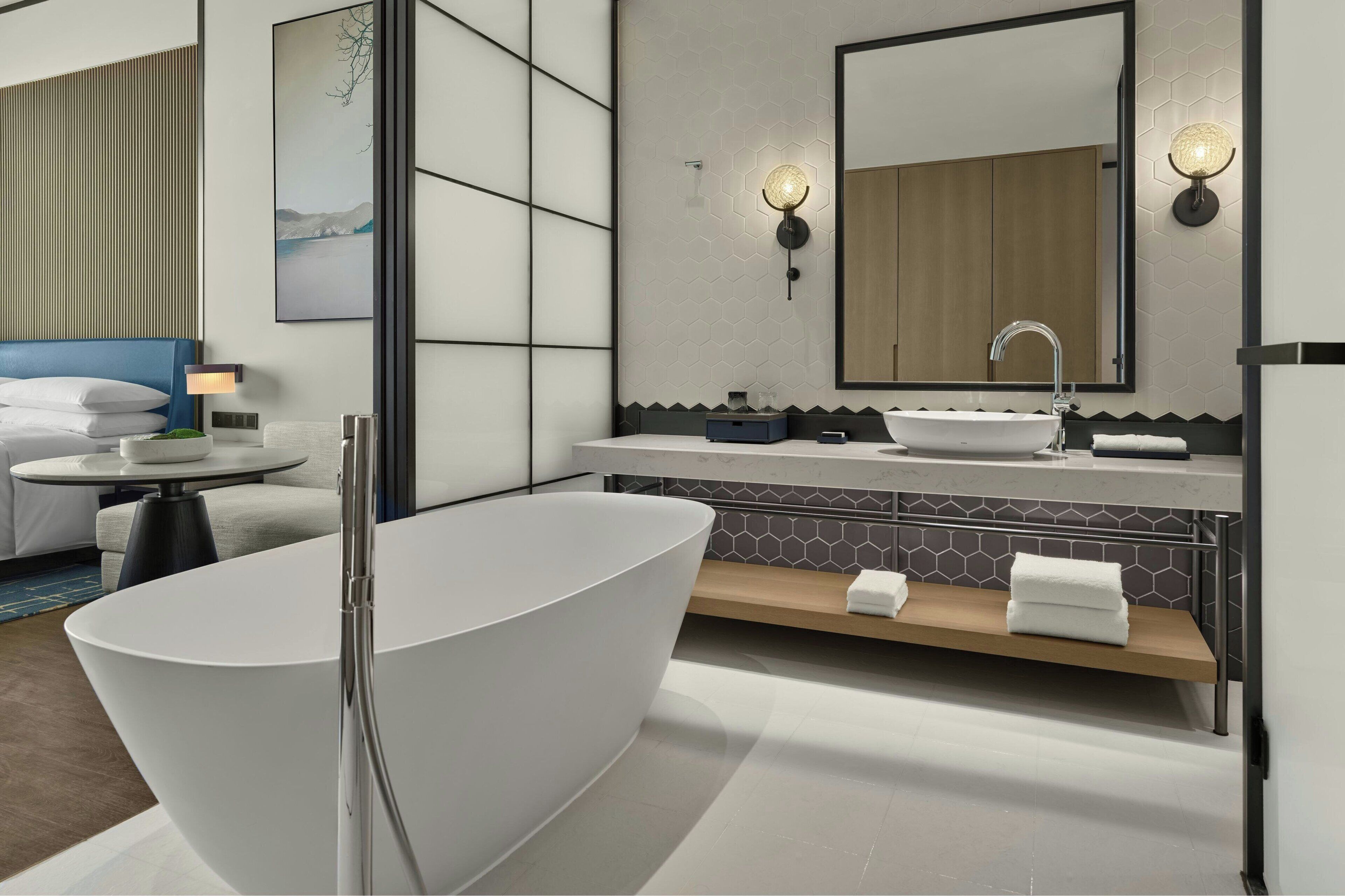 Une salle de bain moderne avec une baignoire sur pieds, un grand miroir et un meuble-lavabo.