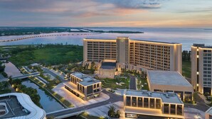Un moderno complejo hotelero con varias torres, un patio ajardinado y vistas al agua.
