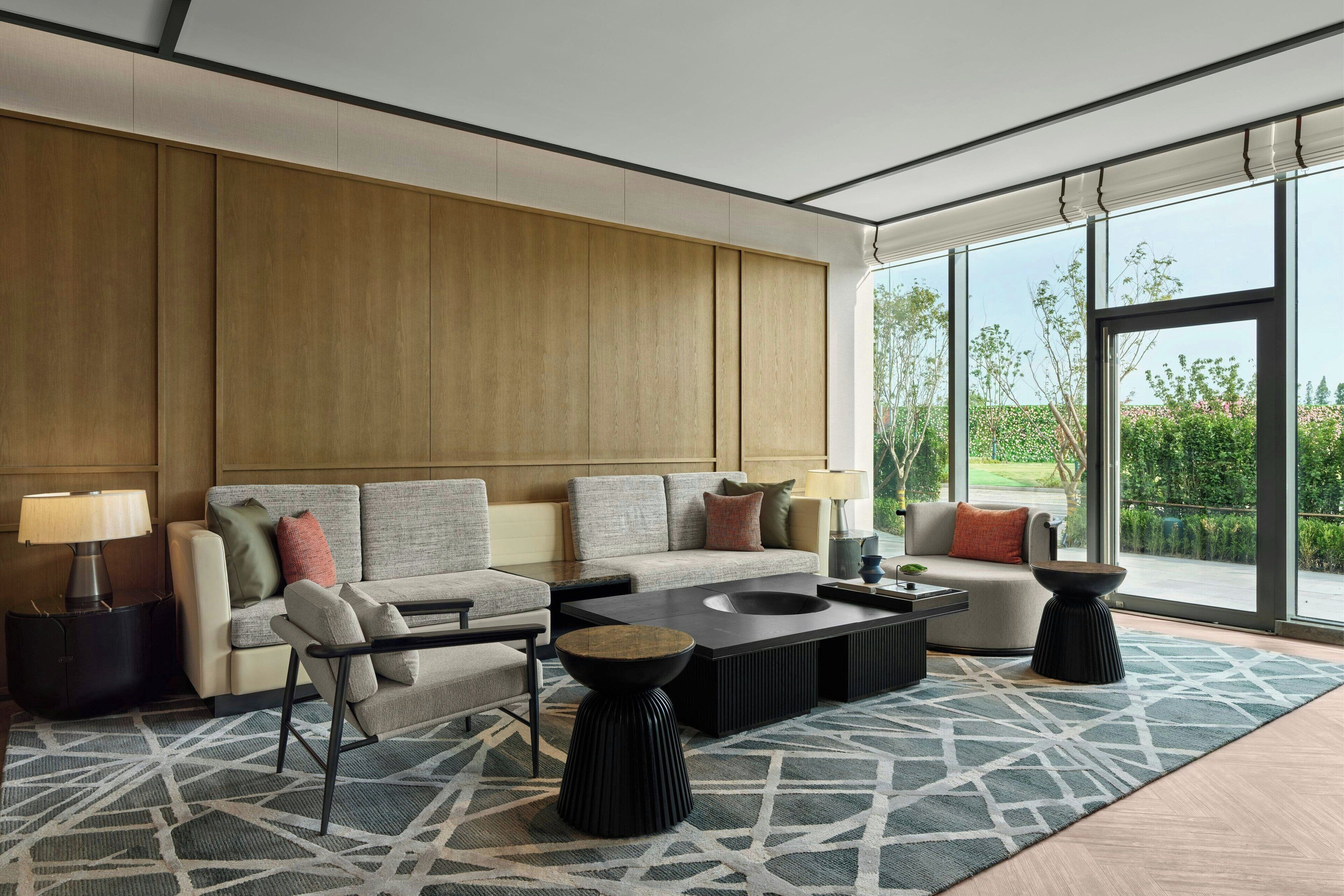A modern living room with a sofa set, coffee table, side tables, and a patterned rug.