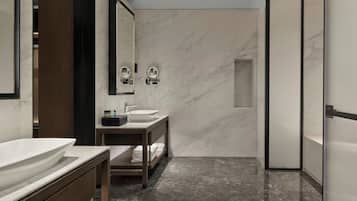 A modern bathroom with a marble vanity, a sink, a mirror, and a shower area.