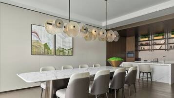A modern dining area with a marble table, grey chairs, and a unique chandelier.