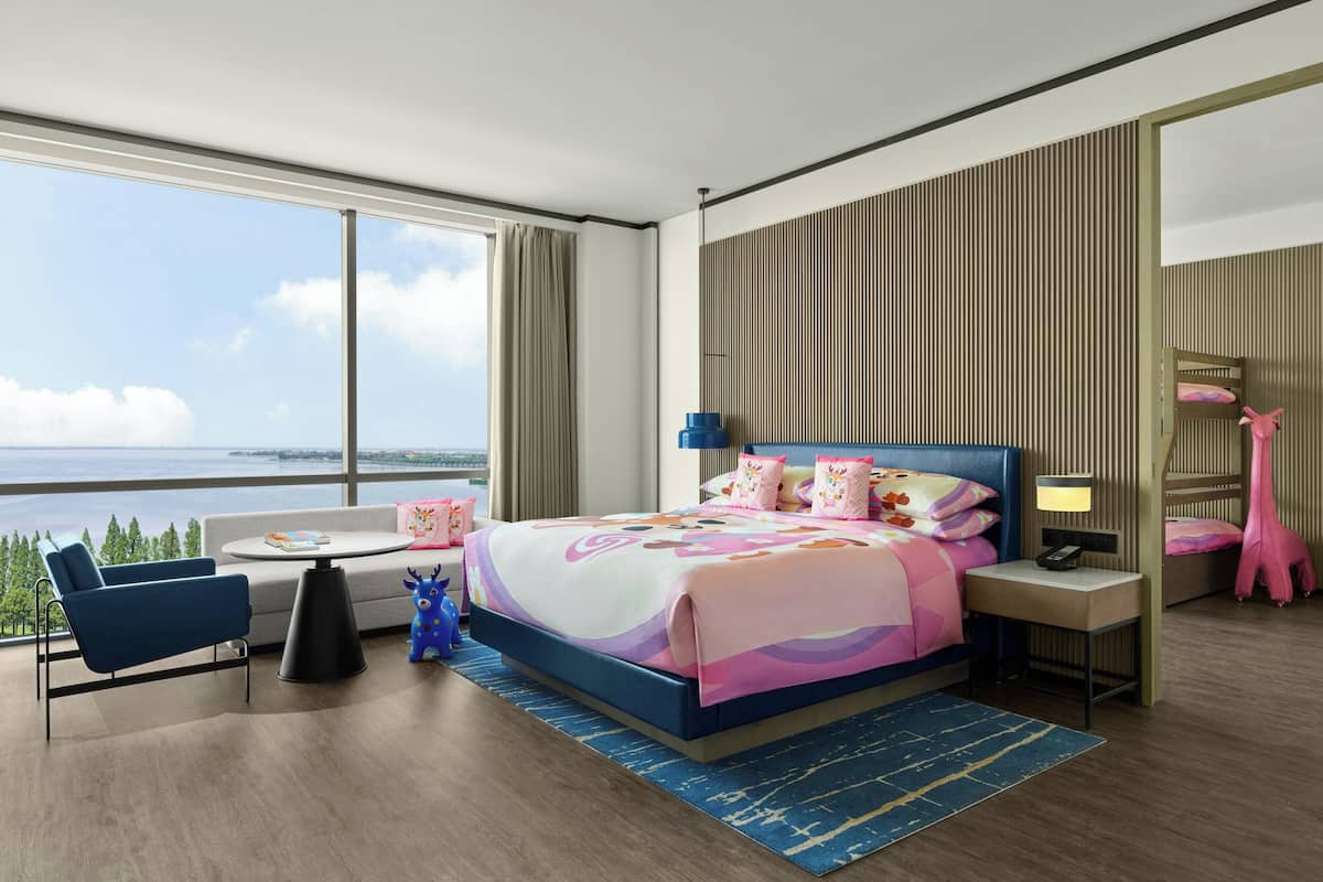 Een moderne hotelkamer met een groot bed, een slaapbank, een bureau en uitzicht op zee.