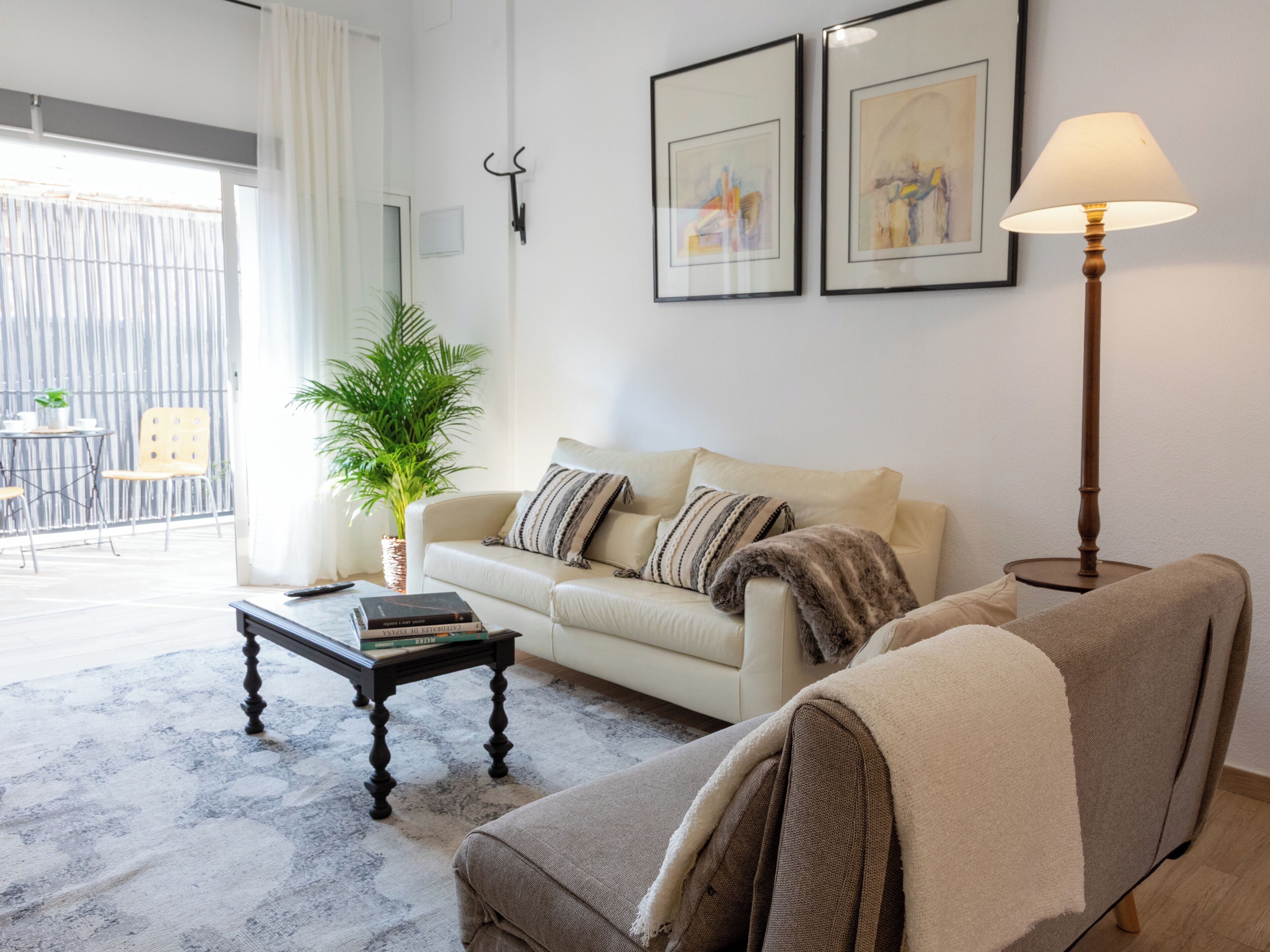 A living room with a sofa, a coffee table, a floor lamp, and a potted plant.