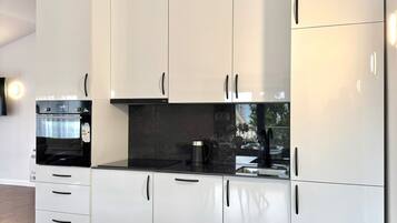 Eine moderne Küche mit weißen Schränken, einer schwarzen Arbeitsplatte und einem eingebauten Backofen.