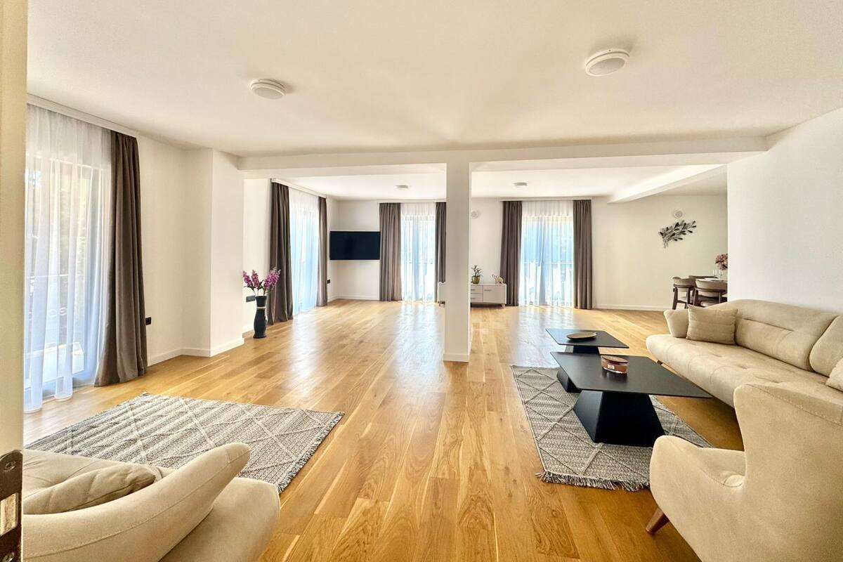 Un salon spacieux doté d’un parquet, d’un canapé, d’une table basse et d’un téléviseur fixé au mur.