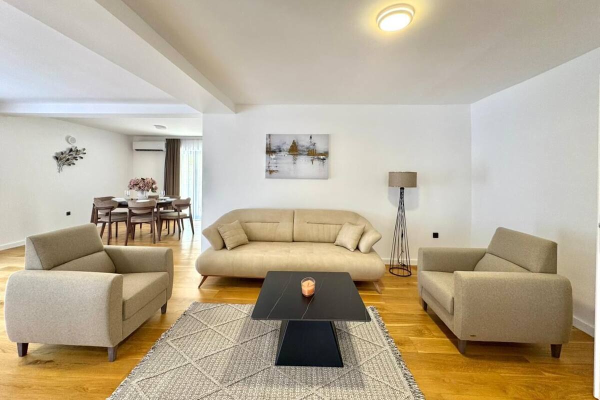 Un salon comprenant un canapé, deux fauteuils, une table basse, un lampadaire et un tableau accroché au mur.