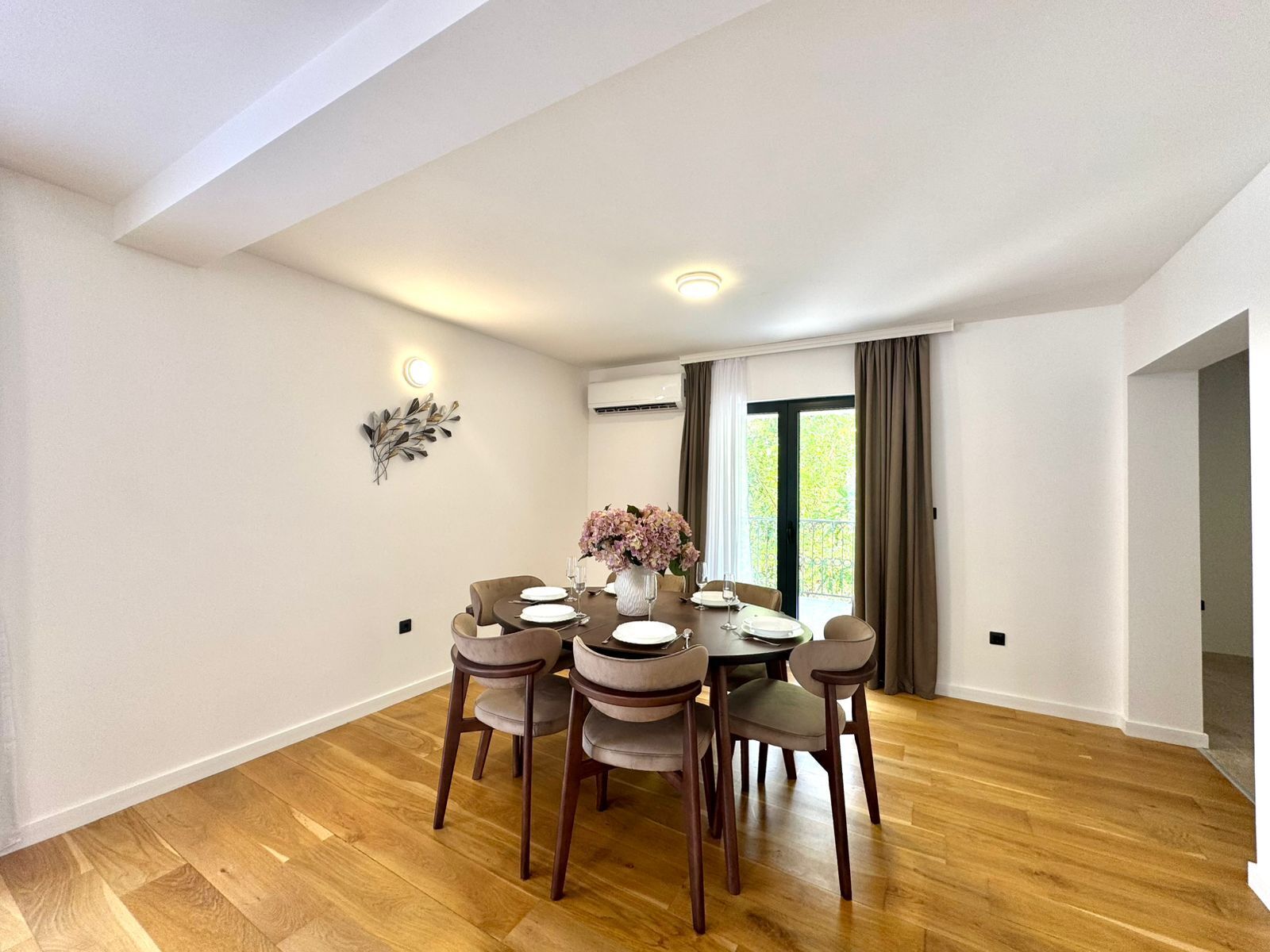 A dining area with a round table, six chairs, and a vase of flowers.