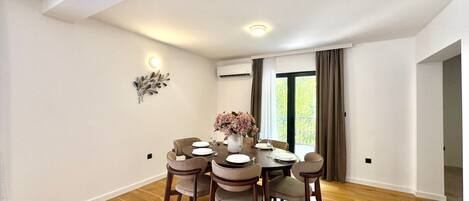 A dining area with a round table, six chairs, and a vase of flowers.