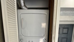 Une petite buanderie équipée d’un lave-linge et d’un sèche-linge à chargement frontal, d’une étiquette ENERGYGUIDE et d’une porte située sur le côté droit.