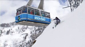 Une télécabine portant l’inscription « Snowbird » transporte des passagers au-dessus d’une montagne enneigée.