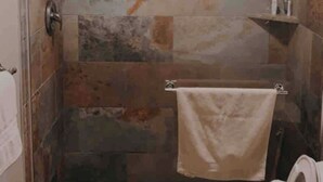 Une douche avec une porte en verre, un porte-serviettes et un mur carrelé.