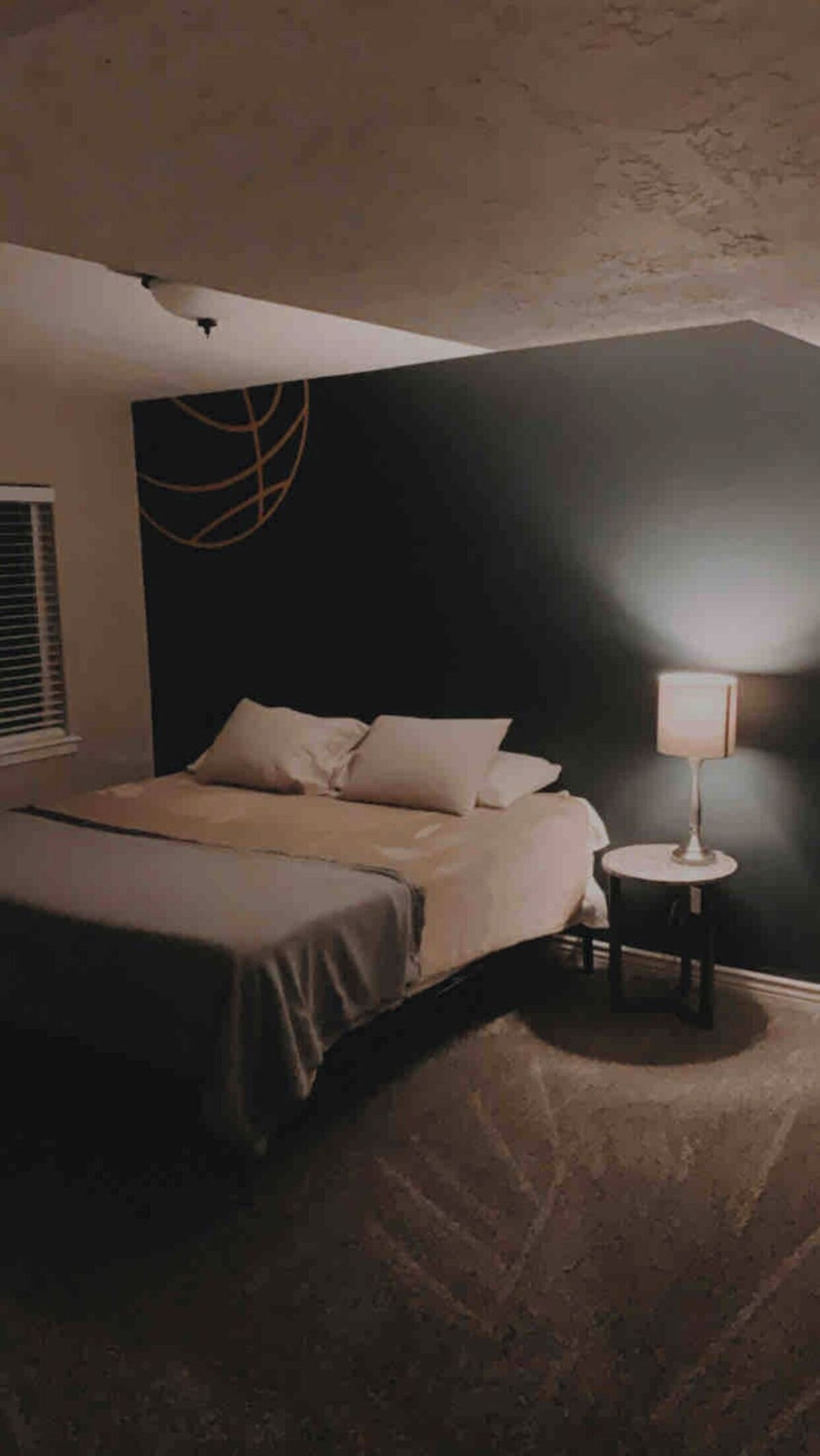 Een slaapkamer met een bed, een bedlampje en een muur met een rond ontwerp.