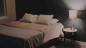 Une chambre à coucher avec un lit, une lampe de chevet et un mur orné d’un motif circulaire.