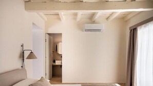 Habitación de hotel minimalista con cama, lámpara, equipo de aire acondicionado y vistas al baño.