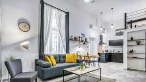 Een moderne woonkamer met een grijze bank, een salontafel en een eetgedeelte met een kroonluchter.