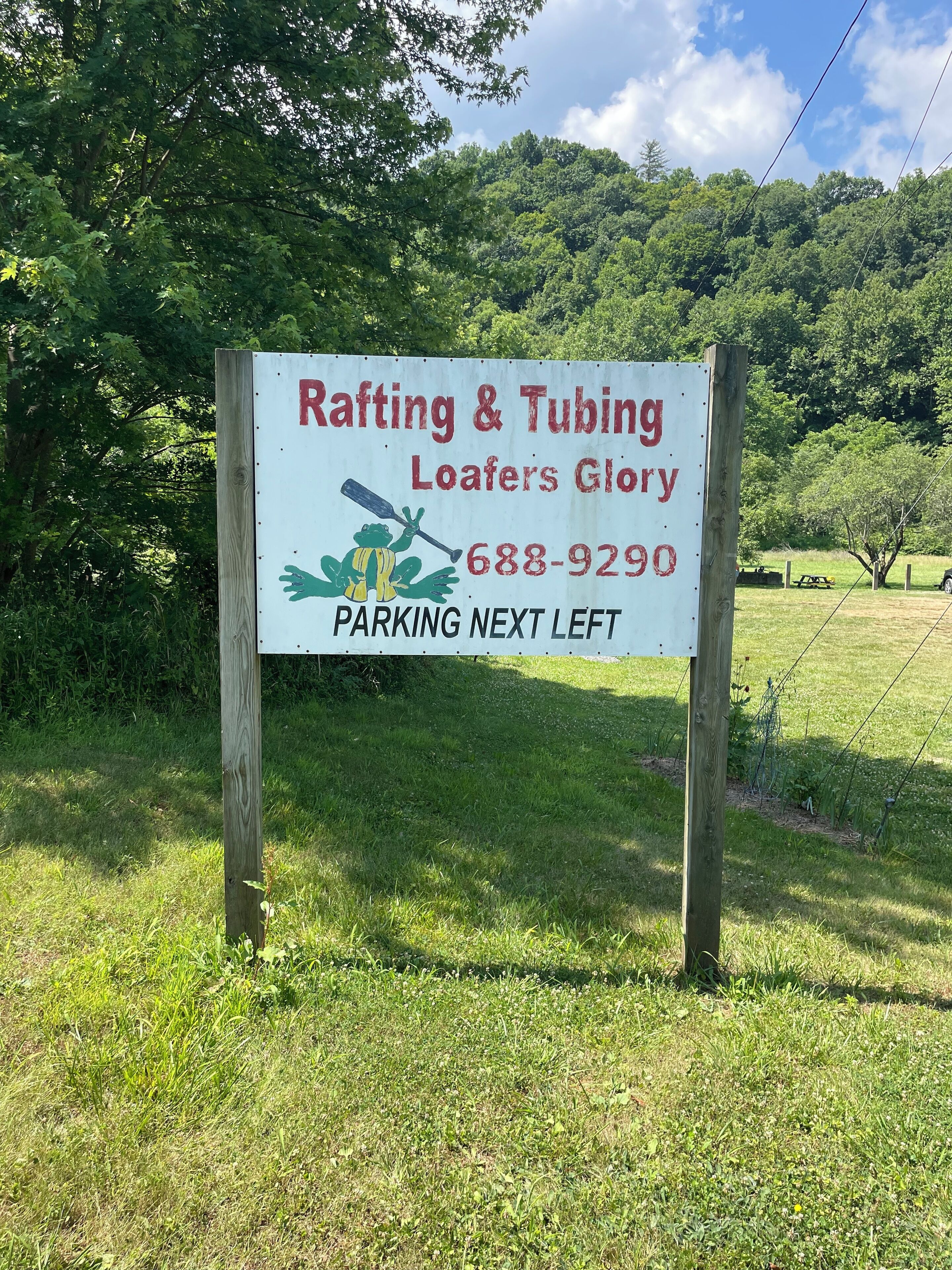 A sign for Rafting & Tubing Loafers Glory with a phone number and directions to parking.