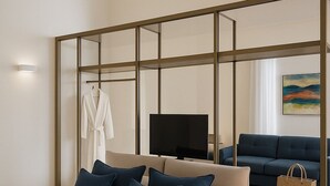 Et moderne hotelværelse med en stor seng, fjernsyn, sofa og et lille bord med lampe.