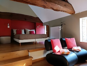 Un dormitorio con cama, una silla, un banco de madera y una ventana.