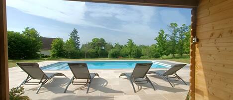 A wooden deck with a pool and lounge chairs.