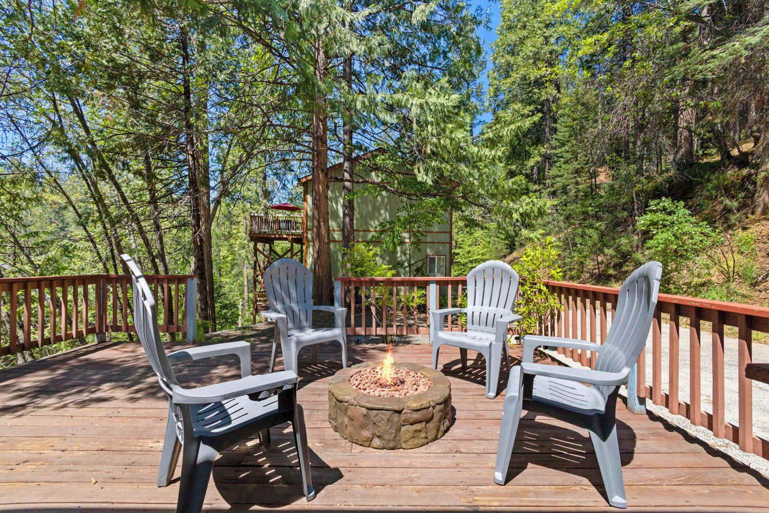 A wooden deck with Adirondack chairs and a stone fire pit.