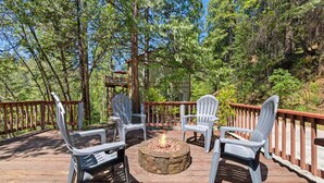 Un patio in legno con poltrone Adirondack e un braciere in pietra.