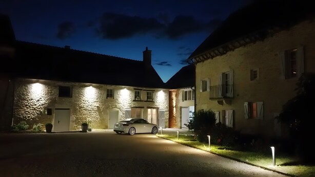 A stone building with a car parked in front, a driveway, and a well-lit entrance. - Guest Room 'Tilleul' with Shared Pool, Shared Terrace and Wi-Fi (Beaumont sur Grosne)