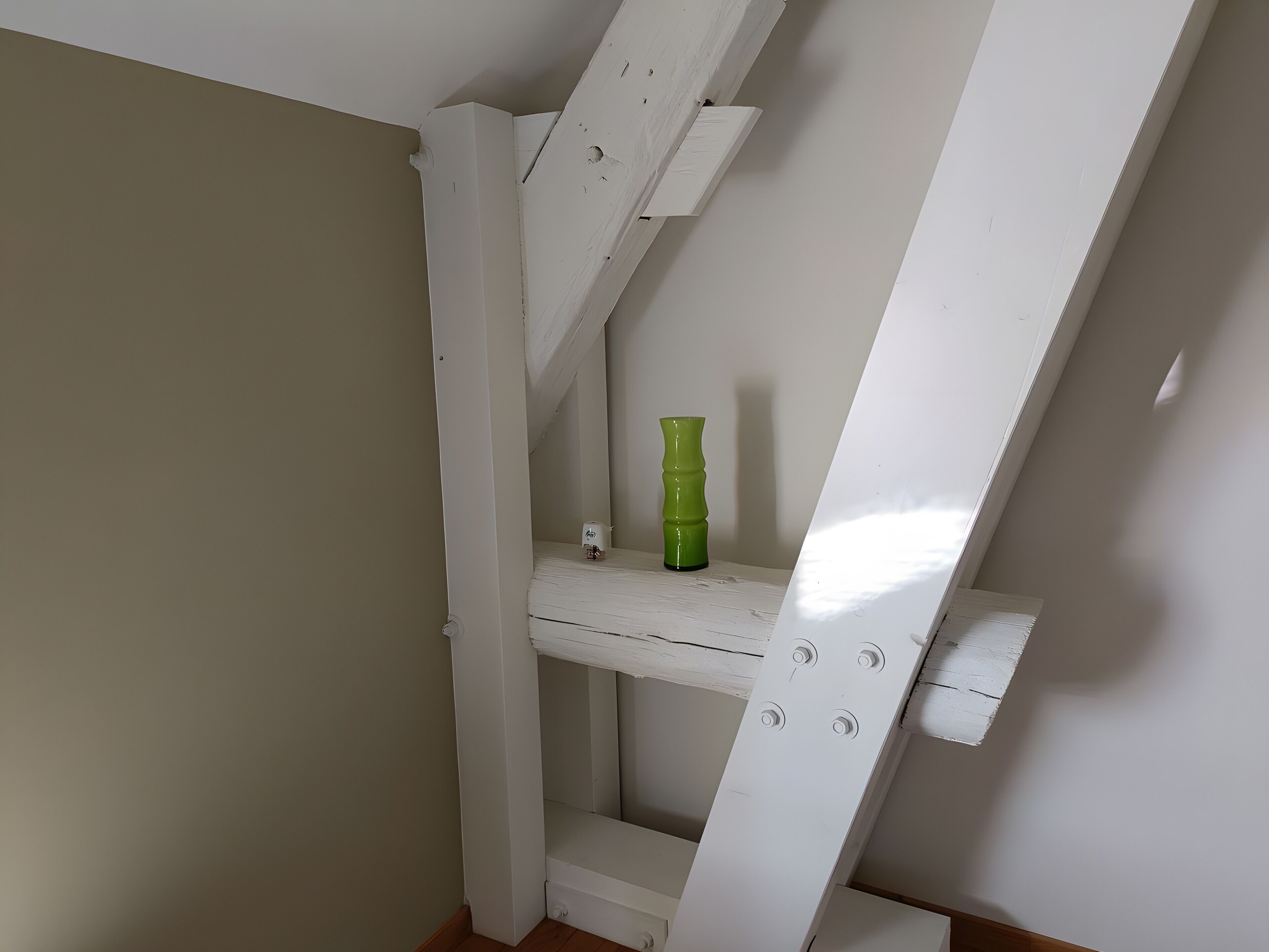 A white wooden staircase with a green vase on the landing.